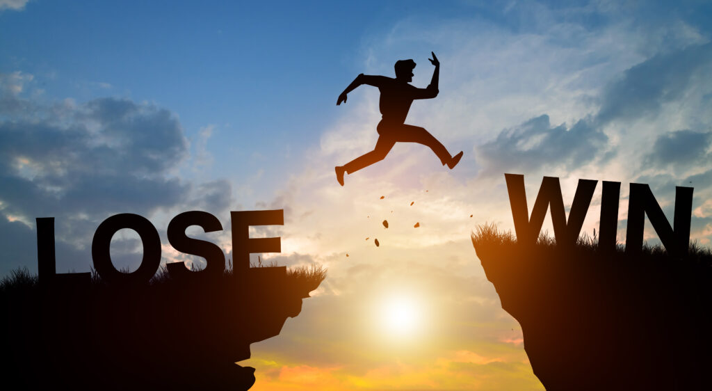 Silhouette man jumping from LOSE to WIN with sunrise